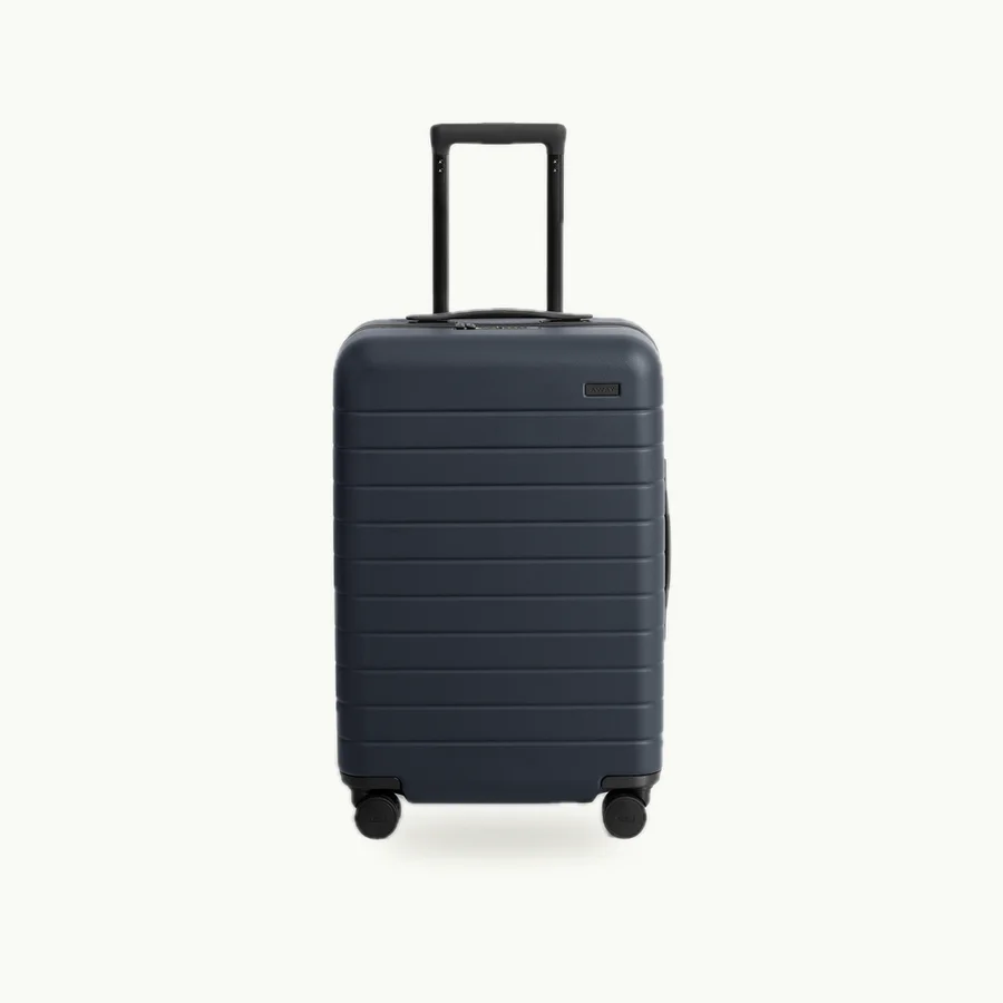 The Bigger Carry-On: Navy hardshell carry-on suitcase with its handle extended