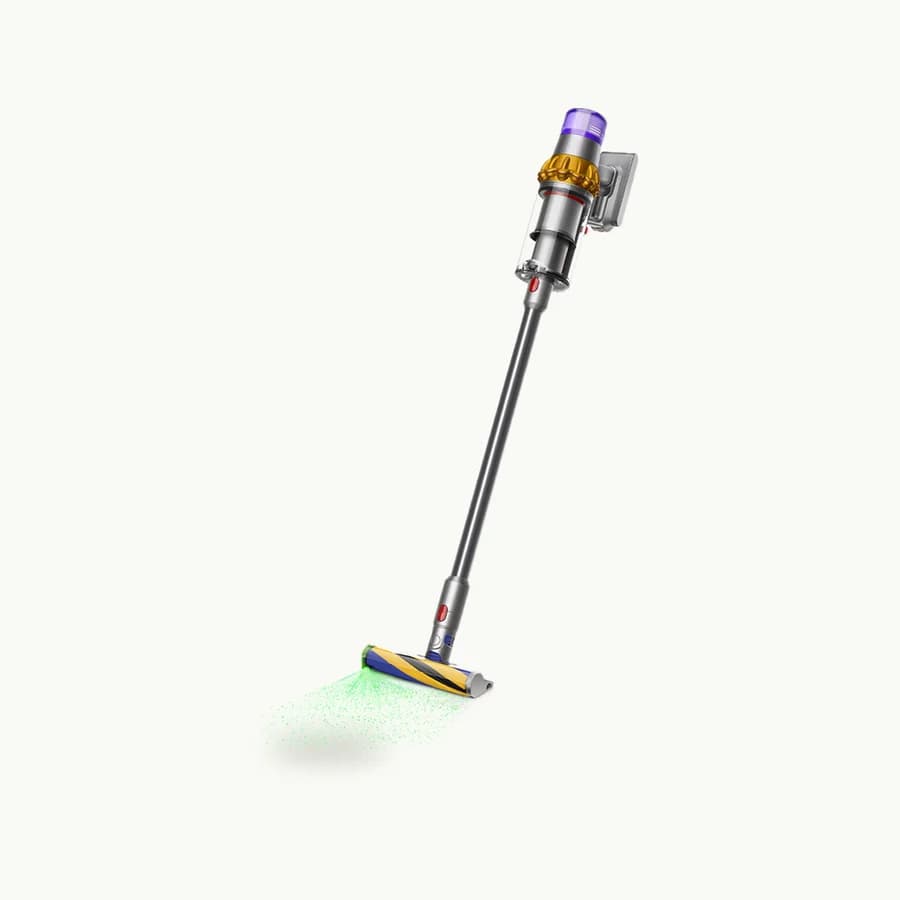 V15 Detect Cordless Vacuum: Yellow and nickel Dyson V15 Detect vacuum shown whole at an angle with its cleaner head emitting green light